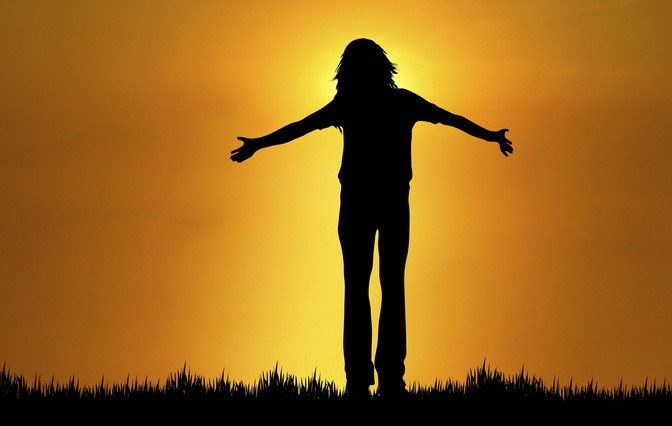 silhouette of woman with open arms at sunset