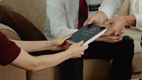 LDS missionaries handing out a Book of Mormon